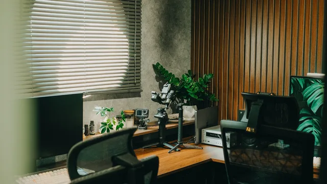 Contemporary home office setup with gadgets, green plants, and natural light through blinds. Planning a move from coworking to a private office